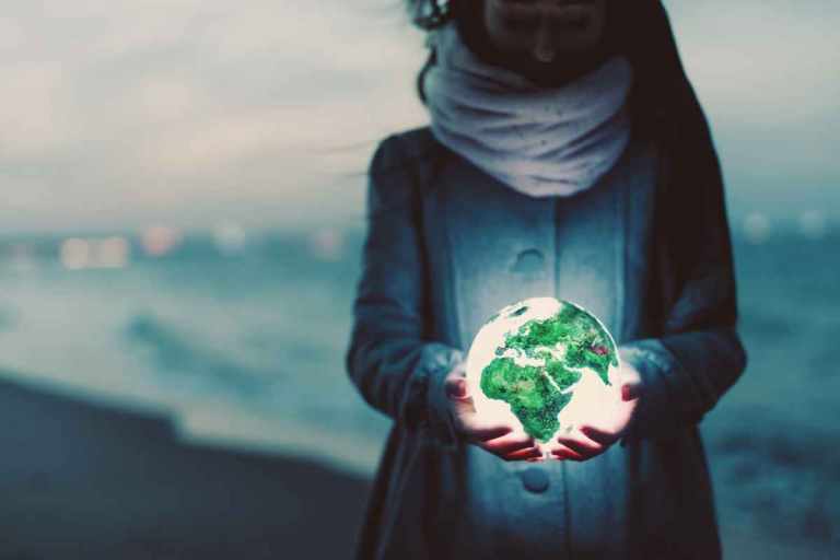 8 Ways to Celebrate Earth Day This Year 28 Image of a woman holding the Earth in her hands on a beach for Gondwana Ecotour's post on Earth Day!